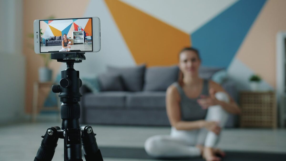Female fitness vlogger using smartphone to record a session in stylish living room.